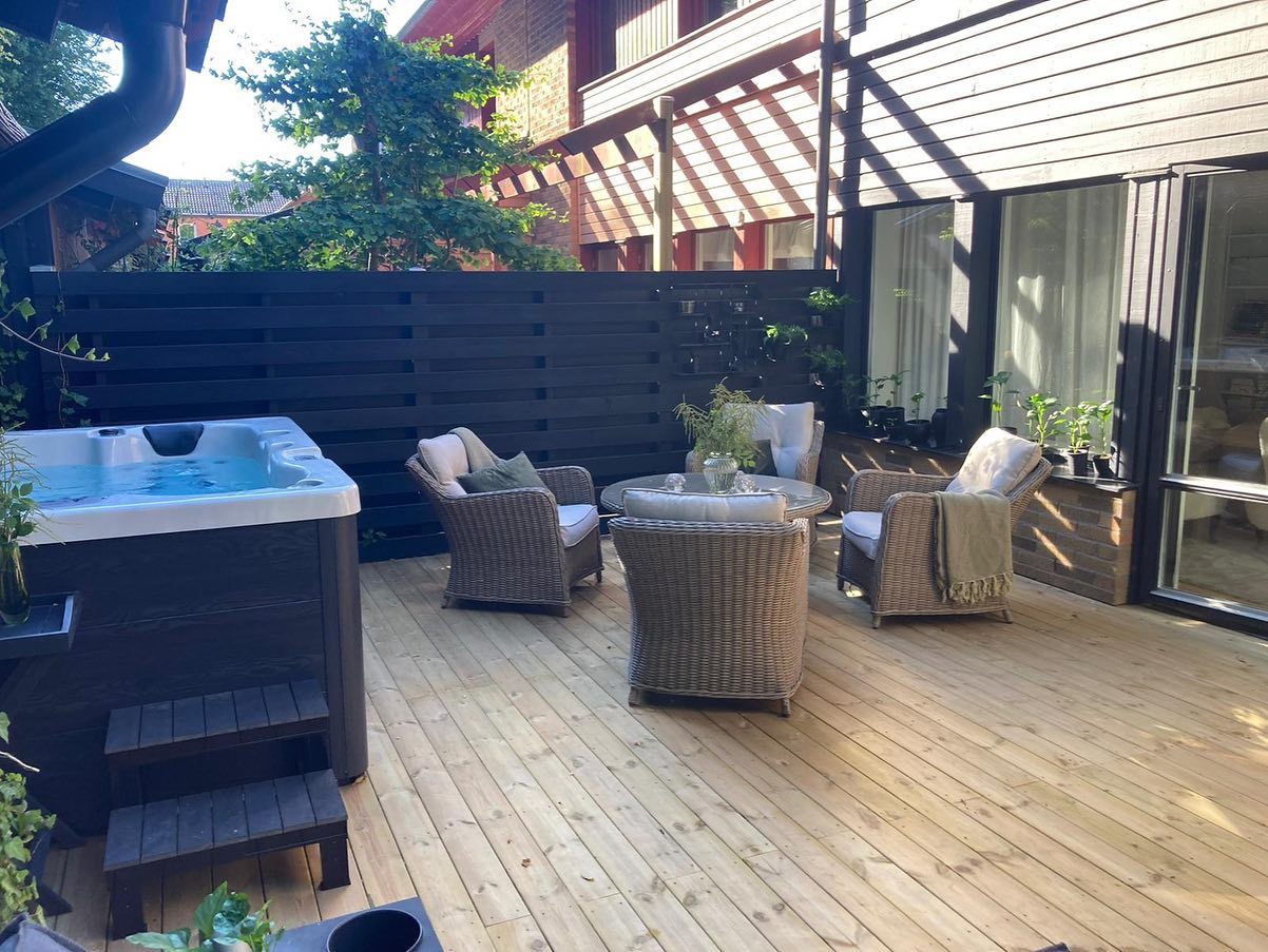 Nybyggd altan till radhus med trätrall, mörkt spaljéstaket, pergola och spabad